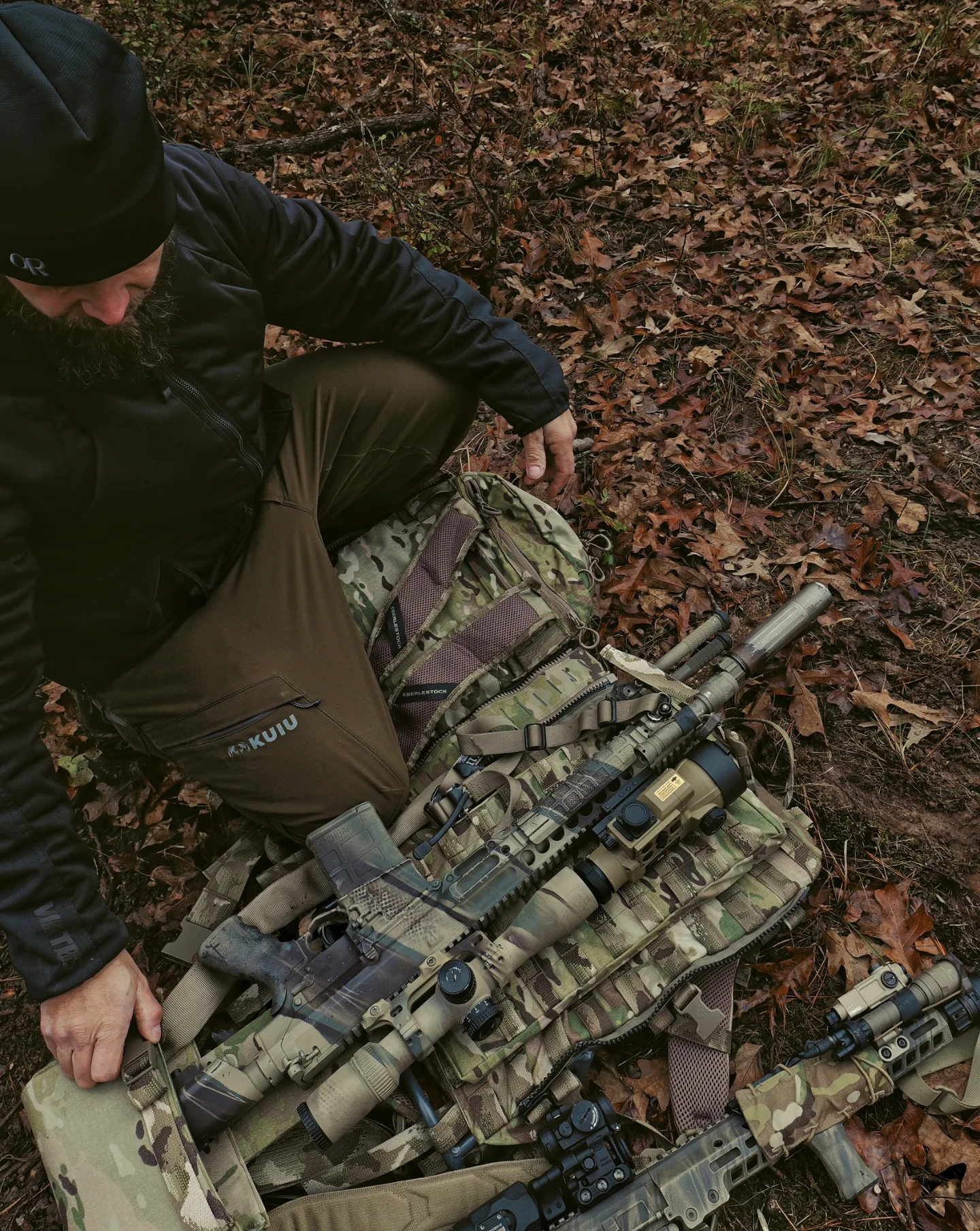 Overhead view of rifles staged on Eberlestock pack in fallen oak leaves