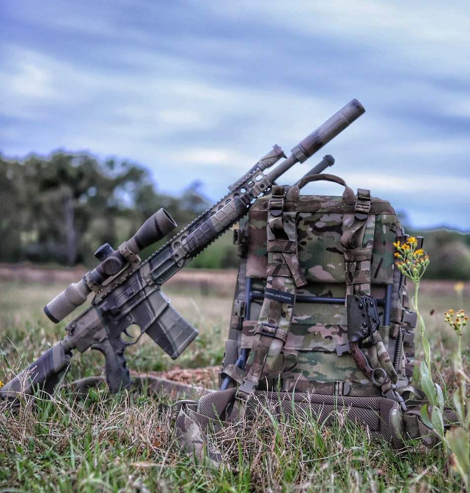 Rifle staged against Eberlestock pack in a pasture